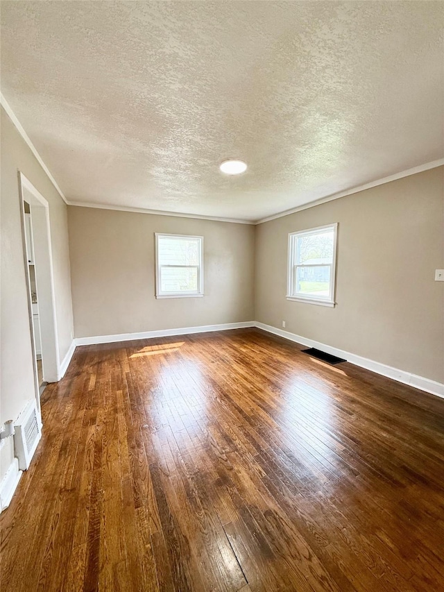 unfurnished room with plenty of natural light, a textured ceiling, hardwood / wood-style flooring, and ornamental molding
