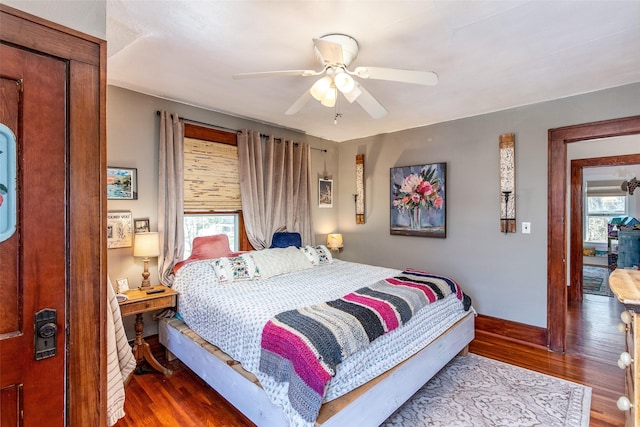 bedroom with baseboards, multiple windows, and wood finished floors