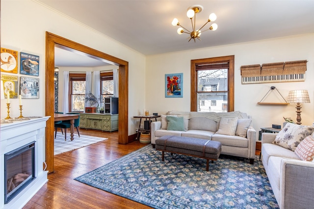 living room with crown molding, a notable chandelier, wood finished floors, and a healthy amount of sunlight