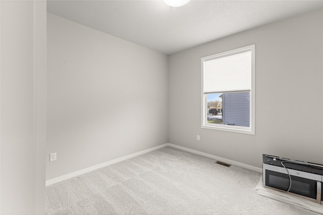 spare room with baseboards, carpet, and visible vents