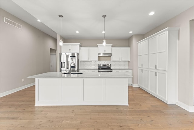 kitchen with visible vents, appliances with stainless steel finishes, under cabinet range hood, white cabinetry, and backsplash