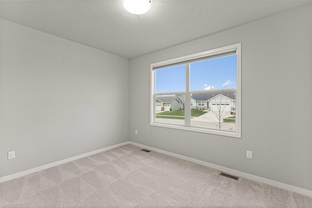empty room featuring visible vents, baseboards, and light colored carpet
