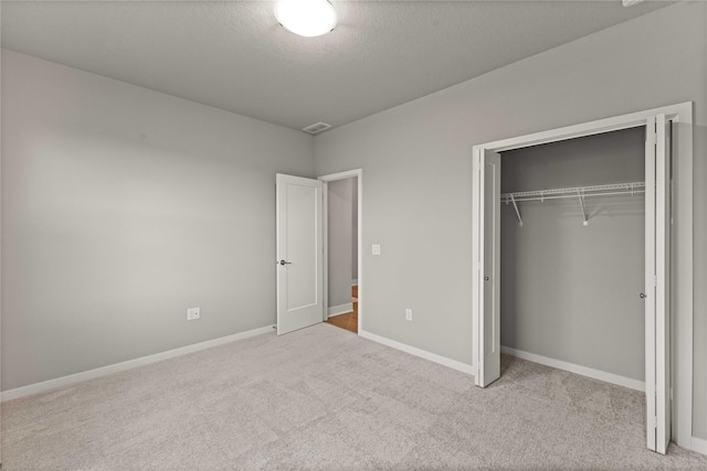 unfurnished bedroom featuring visible vents, a closet, baseboards, and carpet floors