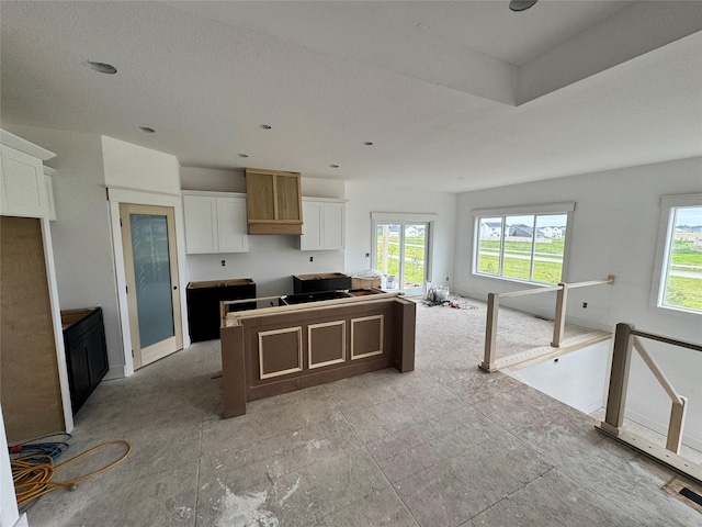 850 NW Frescott Cir, Waukee, IA 50263 - kitchen featuring healthy amount of natural light, white cabinets, a kitchen island, and open floor plan