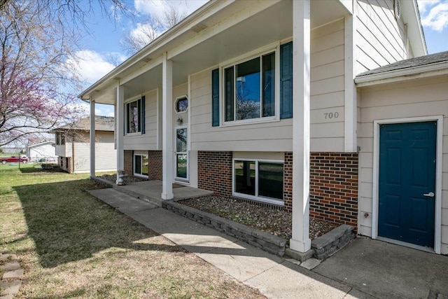 property entrance featuring a yard and brick siding