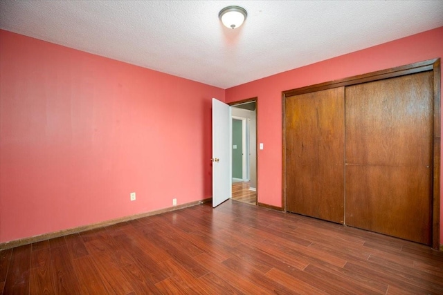 unfurnished bedroom with wood finished floors, a closet, and baseboards