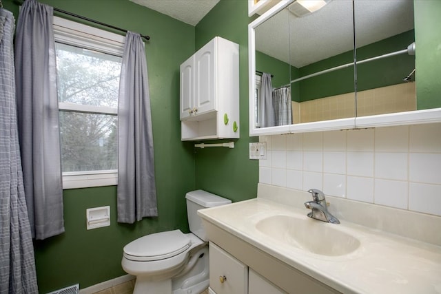 full bath with vanity, baseboards, a textured ceiling, toilet, and decorative backsplash