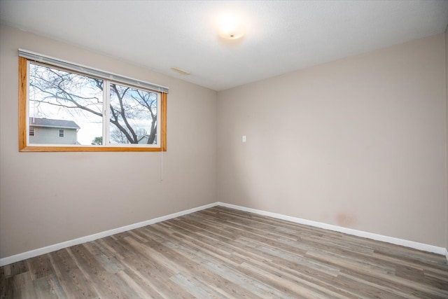 empty room featuring wood finished floors and baseboards