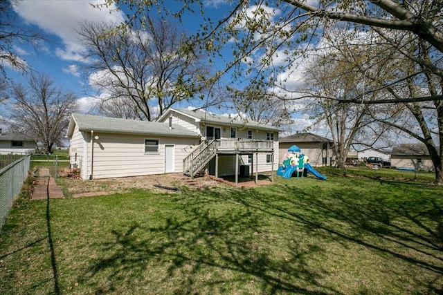 rear view of house with a lawn, a fenced backyard, a playground, and stairs