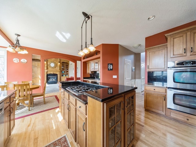 2705 147th St, Urbandale, IA 50323 - kitchen with arched walkways, light wood-style flooring, pendant lighting, and appliances with stainless steel finishes