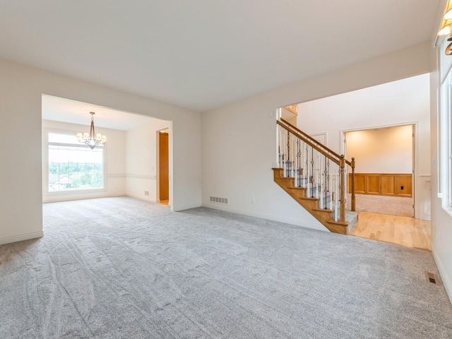 2705 147th St, Urbandale, IA 50323 - unfurnished living room with carpet floors, a chandelier, and stairway