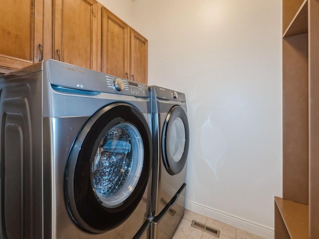 2705 147th St, Urbandale, IA 50323 - washroom featuring independent washer and dryer, cabinet space, and light tile patterned floors