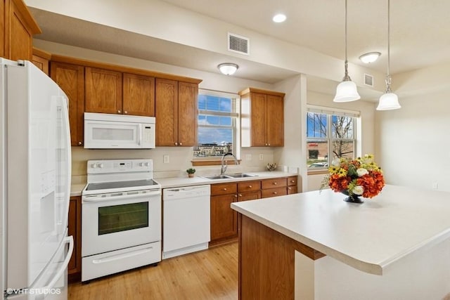 1370 SW Magazine Rd Unit 101, Ankeny, IA 50023 - kitchen featuring brown cabinets, visible vents, a sink, and white appliances