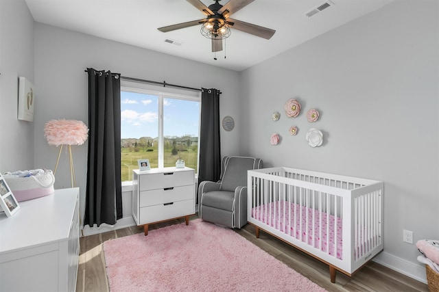 16318 Goldenrod Dr, Urbandale, IA 50323 - bedroom featuring wood finished floors, baseboards, visible vents, and a crib