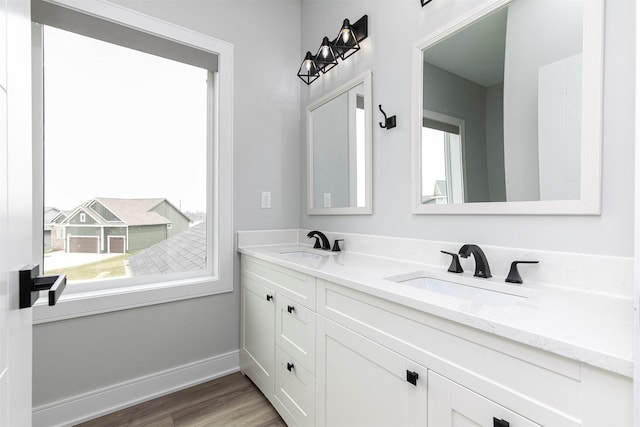 16318 Goldenrod Dr, Urbandale, IA 50323 - bathroom featuring wood finished floors, double vanity, a sink, and baseboards
