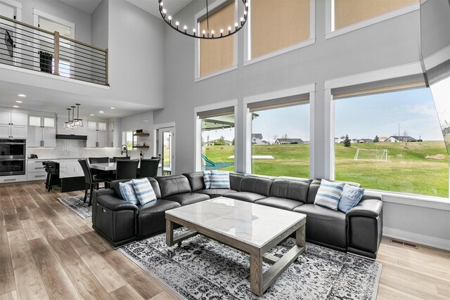 16318 Goldenrod Dr, Urbandale, IA 50323 - living room featuring visible vents, light wood-style floors, a notable chandelier, and a towering ceiling