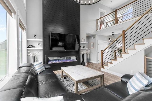 16318 Goldenrod Dr, Urbandale, IA 50323 - living room with a fireplace, a chandelier, wood finished floors, a high ceiling, and stairs