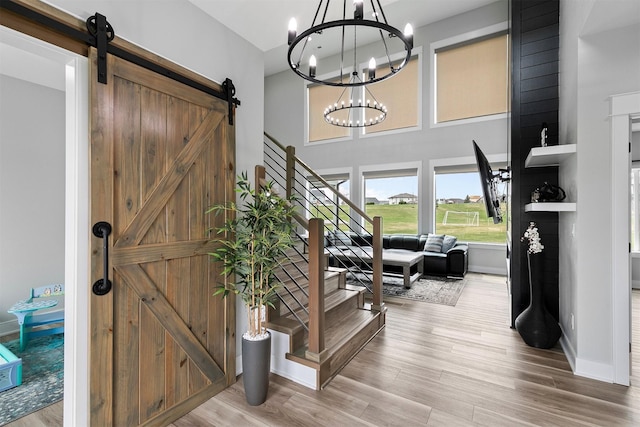 16318 Goldenrod Dr, Urbandale, IA 50323 - foyer with stairway, a chandelier, a barn door, wood finished floors, and baseboards