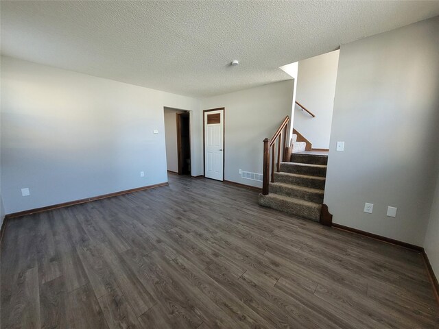 1761 E Lacona Ave, Des Moines, IA 50320 - unfurnished living room featuring dark wood-type flooring, a textured ceiling, visible vents, stairway, and baseboards