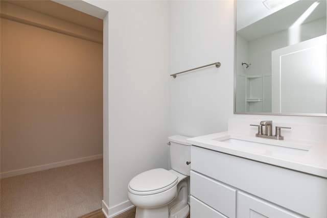 bathroom featuring a shower, vanity, baseboards, and toilet