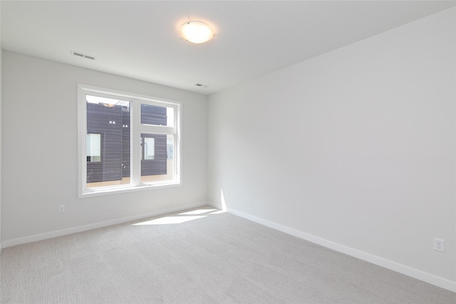 spare room featuring carpet, visible vents, and baseboards