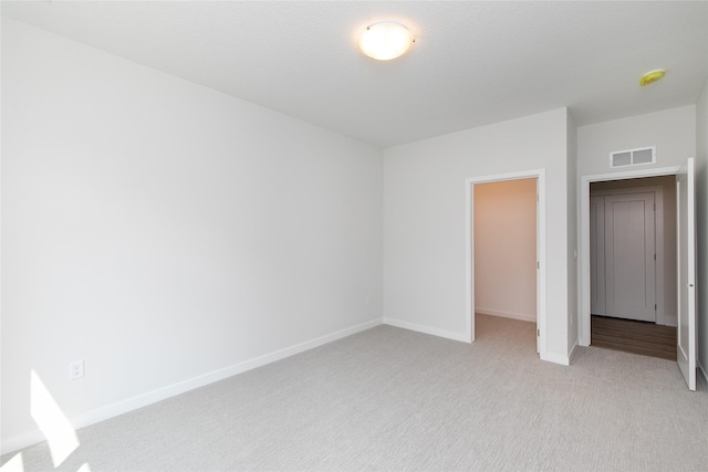 unfurnished bedroom featuring light carpet, visible vents, and baseboards