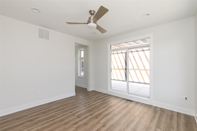 unfurnished room featuring light wood finished floors, baseboards, a ceiling fan, and visible vents