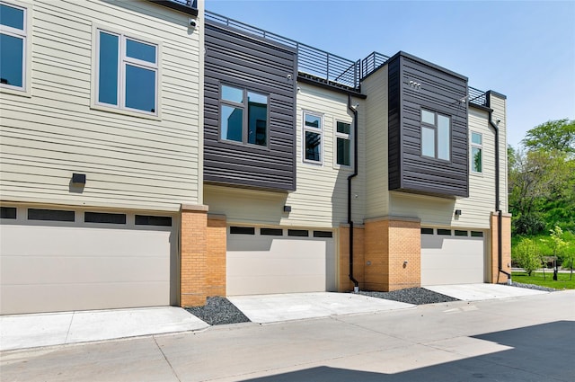view of front of property featuring an attached garage, concrete driveway, and brick siding