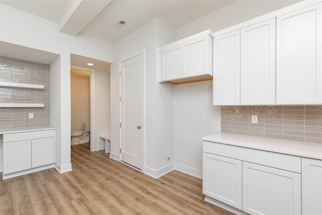 kitchen featuring tasteful backsplash, light countertops, and light wood finished floors