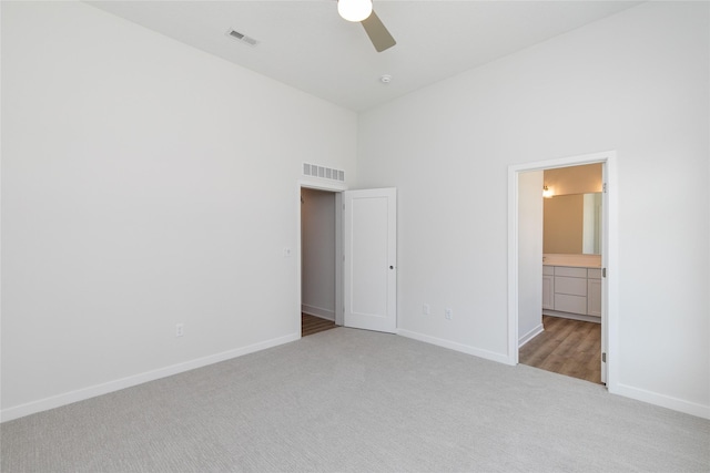 unfurnished bedroom featuring visible vents, baseboards, carpet, and a towering ceiling