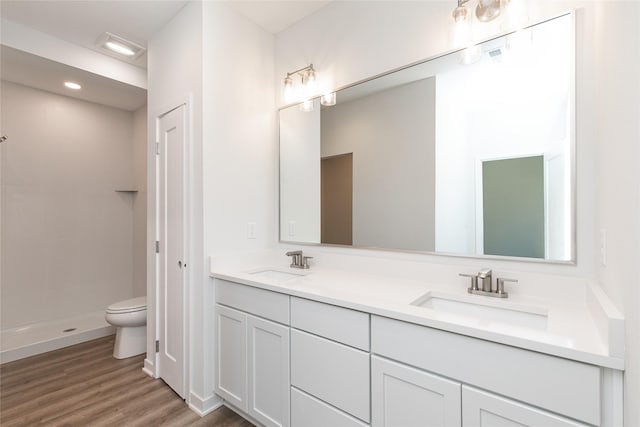 full bathroom with tiled shower, a sink, toilet, and wood finished floors