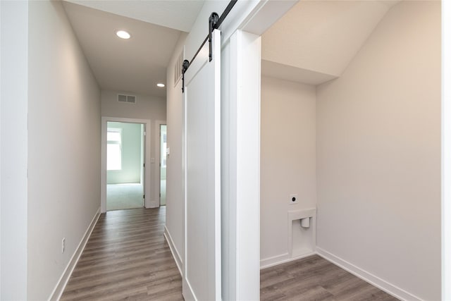 corridor with visible vents, baseboards, a barn door, recessed lighting, and wood finished floors