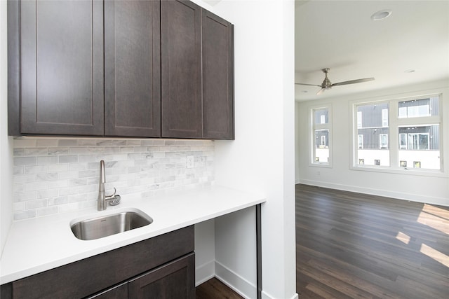 kitchen with light countertops, backsplash, dark brown cabinets, ceiling fan, and a sink