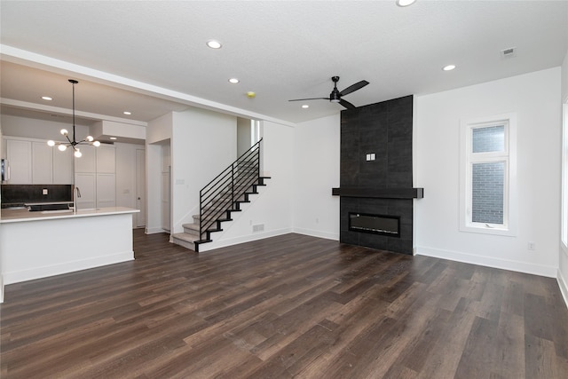 unfurnished living room featuring recessed lighting, stairway, dark wood-style floors, visible vents, and ceiling fan with notable chandelier