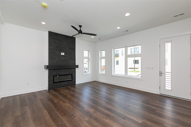 unfurnished living room with visible vents, baseboards, a ceiling fan, dark wood finished floors, and a large fireplace