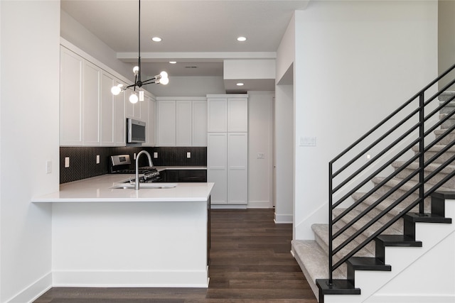 kitchen with tasteful backsplash, a sink, appliances with stainless steel finishes, a peninsula, and white cabinetry