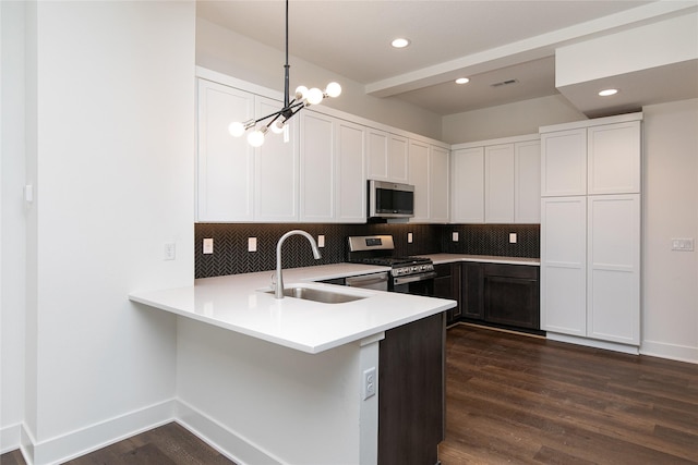 kitchen with a sink, light countertops, stainless steel appliances, dark wood-type flooring, and decorative backsplash