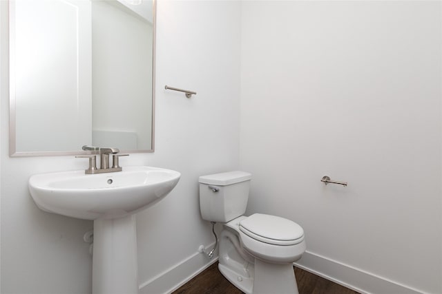 bathroom with baseboards, toilet, and wood finished floors