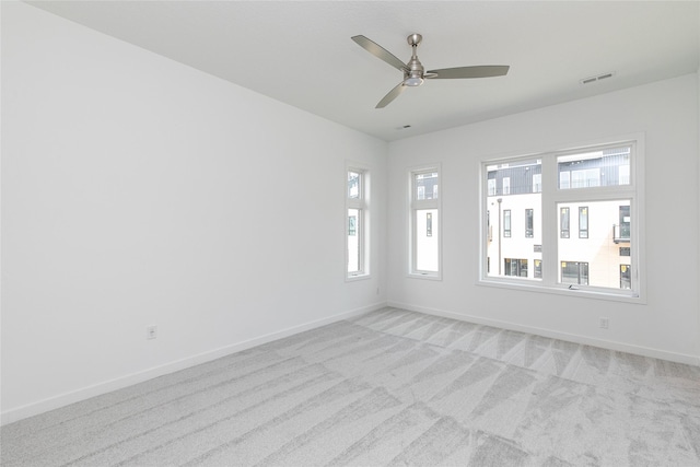 empty room with visible vents, baseboards, plenty of natural light, and light colored carpet