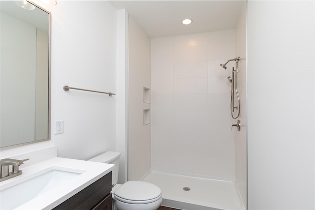 bathroom with recessed lighting, tiled shower, vanity, and toilet