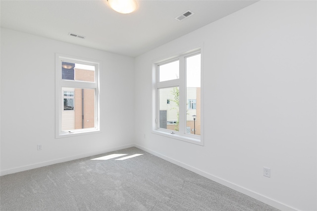 carpeted spare room featuring visible vents and baseboards