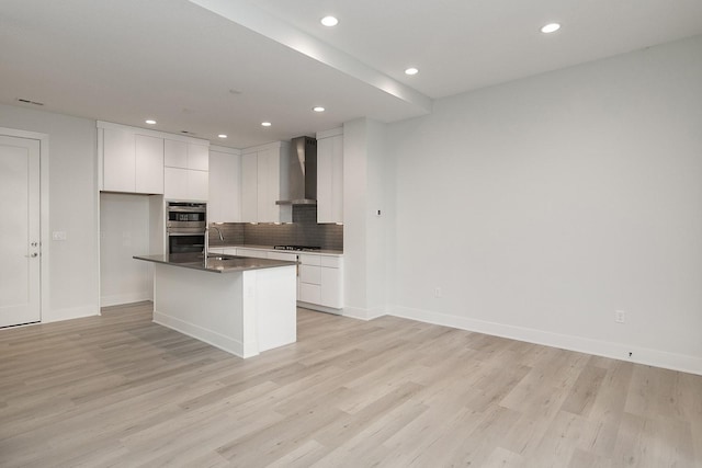 213 Maple St, Des Moines, IA 50309 - kitchen with white cabinets, light wood-style flooring, wall chimney exhaust hood, and dark countertops