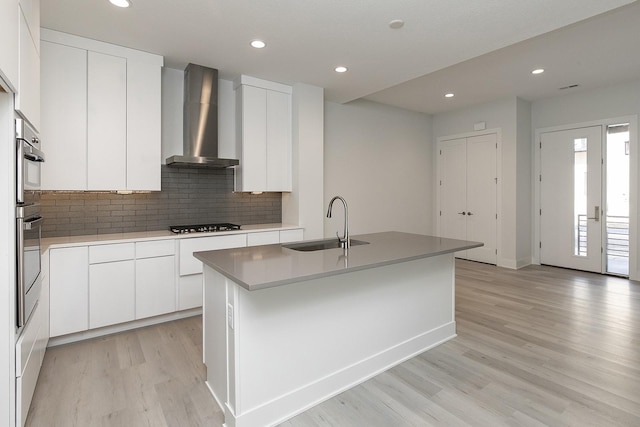213 Maple St, Des Moines, IA 50309 - kitchen featuring a sink, wall chimney range hood, light wood finished floors, stainless steel oven, and decorative backsplash