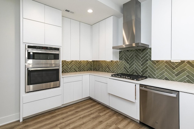 209 Maple St, Des Moines, IA 50309 - kitchen featuring wall chimney exhaust hood, visible vents, appliances with stainless steel finishes, light countertops, and backsplash