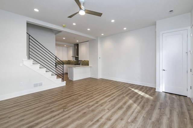 209 Maple St, Des Moines, IA 50309 - unfurnished living room with light wood-type flooring, a ceiling fan, visible vents, and stairs