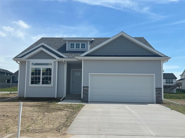 570 SE Hollow Ct, West Des Moines, IA 50265 - view of front of house with driveway, stone siding, an attached garage, and a shingled roof