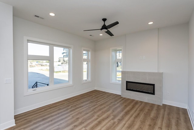859 E 2nd St, Des Moines, IA 50309 - unfurnished living room with wood finished floors, ceiling fan, a tiled fireplace, and visible vents