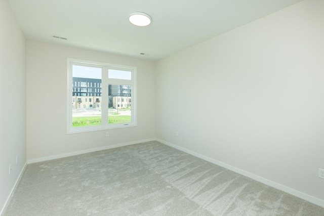 unfurnished room featuring visible vents, light colored carpet, and baseboards