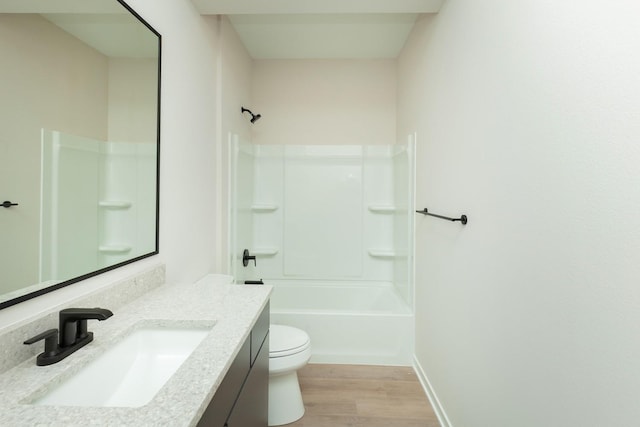 bathroom with bathtub / shower combination, vanity, toilet, wood finished floors, and baseboards