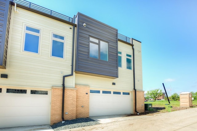 exterior space with concrete driveway, brick siding, and an attached garage